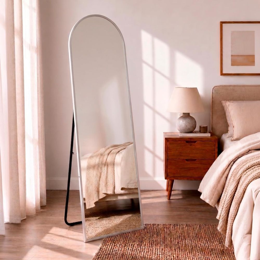 Espejo curvo plateado de pared aportando luminosidad a una habitación compacta.
