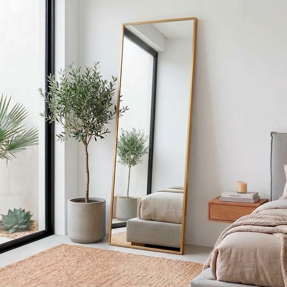 Espejo vestidor de cuerpo entero dorado con soporte trasero desplegado en la habitación.