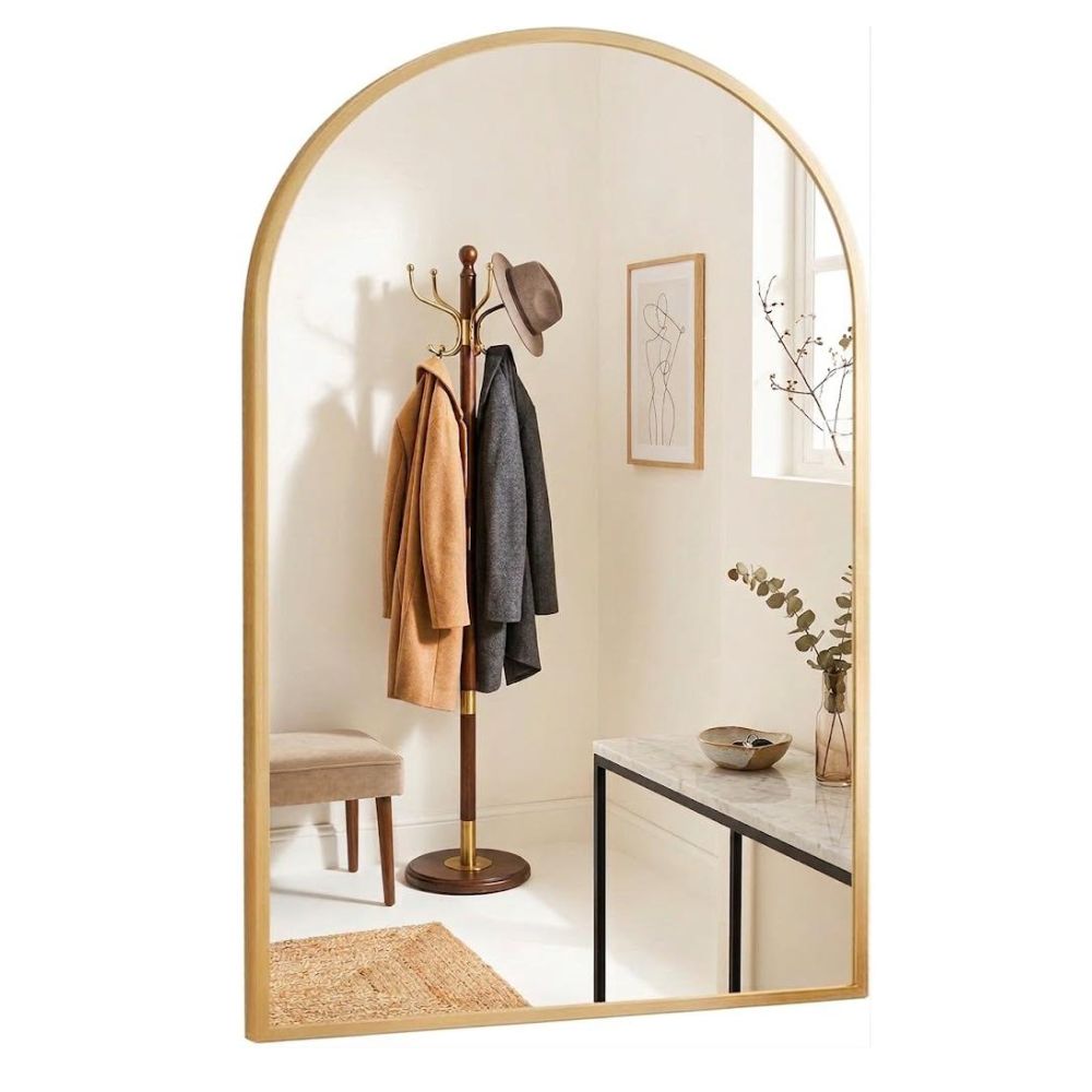 Espejo ventana arqueado Marctani con marco de aluminio dorado en un recibidor.